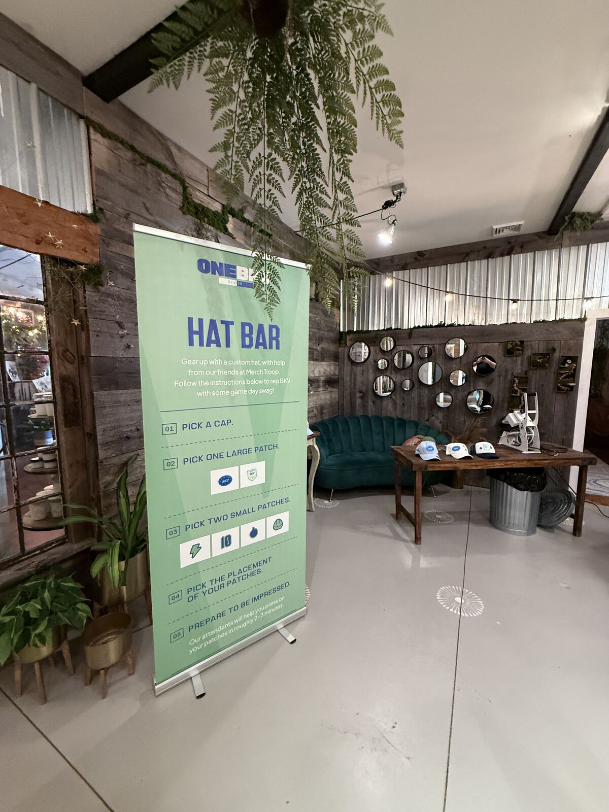 Person operating a heat press machine with colorful hat blanks and finished products on display shelf