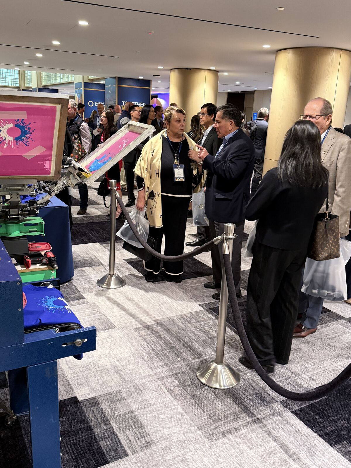 Trade show or expo floor with multiple booths displaying printed merchandise and promotional items